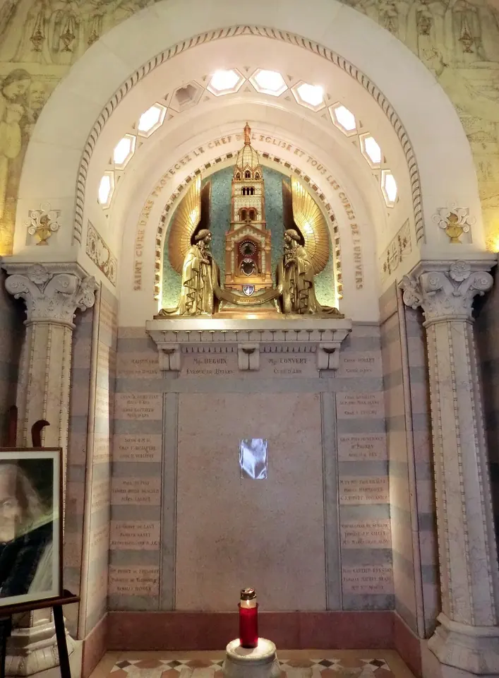 Interior of a small domed chapel with a tall gilded reliquary in a lit niche above a marble altar