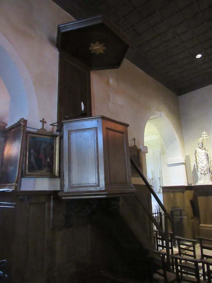 Simple wooden pulpit with a small sounding board mounted on the plastered wall of a village church