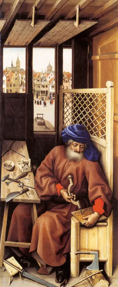 An elderly bearded carpenter in a red robe and blue turban drills a small wooden board at his bench, surrounded by tools, with a Flemish town square visible through the window behind him