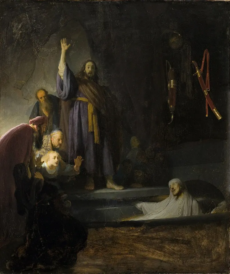 Pintura oscura de Rembrandt con Cristo de pie y el brazo levantado sobre una tumba abierta, de la que se incorpora un Lázaro pálido envuelto en su sudario mientras los presentes retroceden