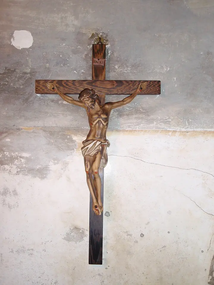 A carved wooden crucifix hanging on a worn, pale plaster wall