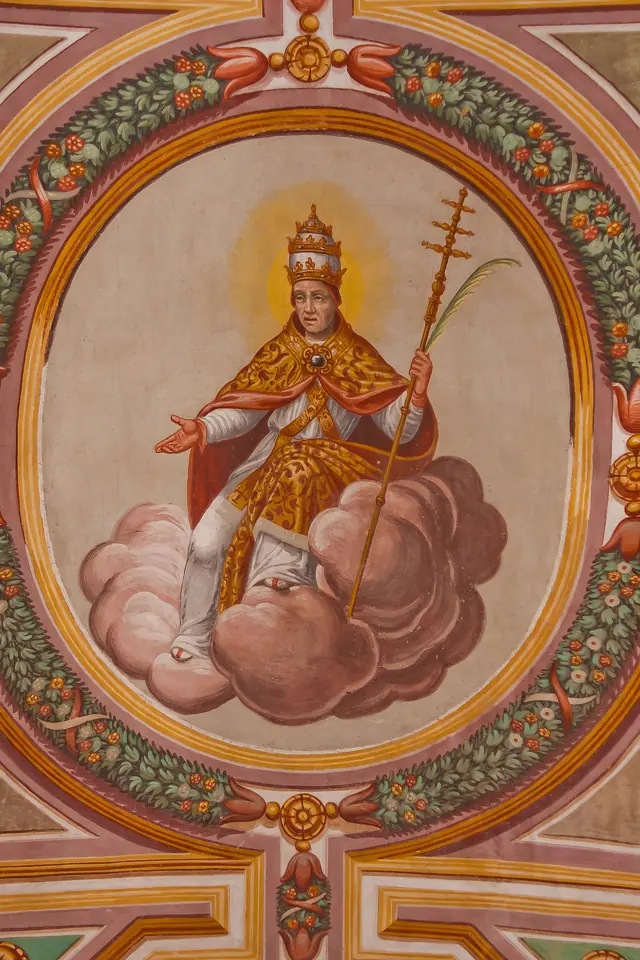 Ceiling painting in a round garland frame showing a pope in a golden tiara and red and gold cope seated on clouds, holding a papal cross and a martyr's palm