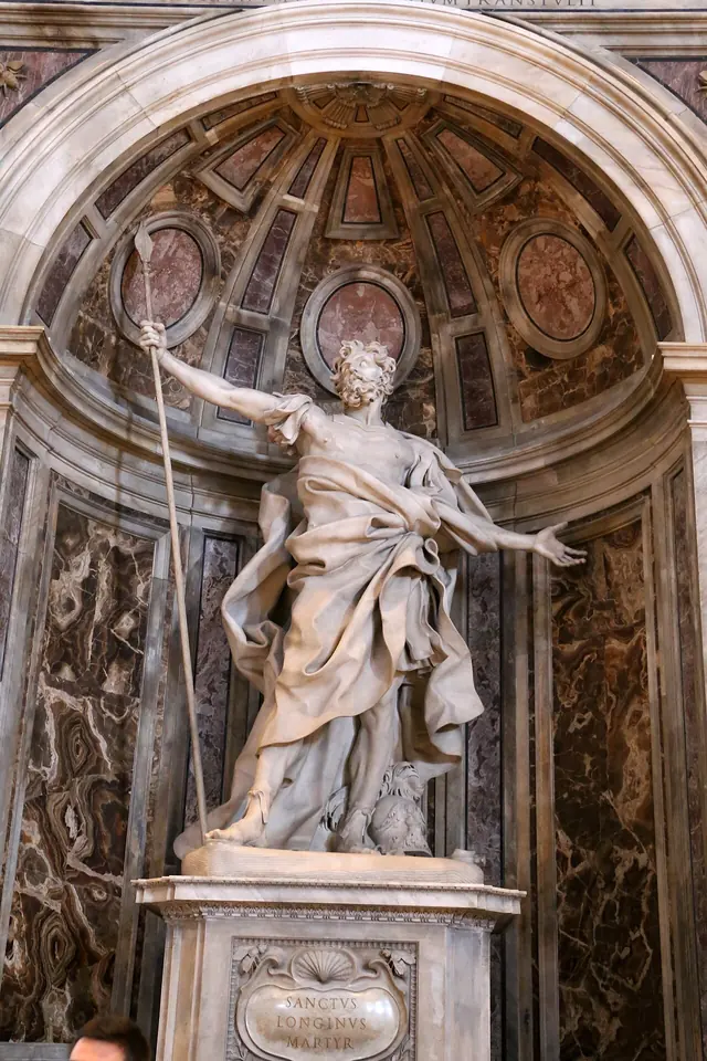 Bernini's colossal white marble Longinus in a niche of St. Peter's, arms flung wide, head tilted up, a tall lance in his right hand and his cloak swirling around him