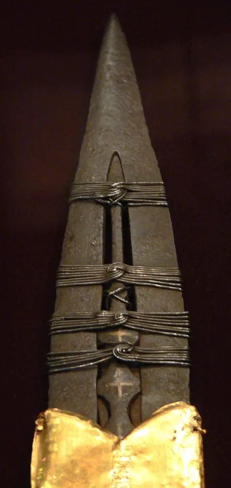 Close-up of the iron blade of the Holy Lance of Vienna, bound with wire and a gold sleeve, against a dark background