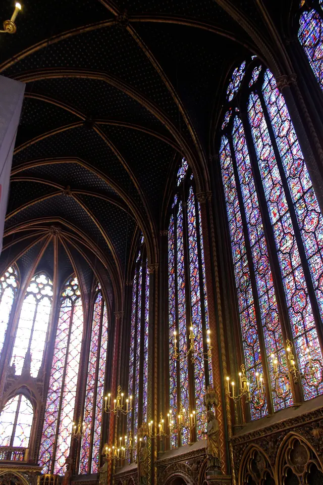 The upper chapel of the Sainte-Chapelle, with tall walls of blue and red stained glass rising to a dark blue vault scattered with gold stars