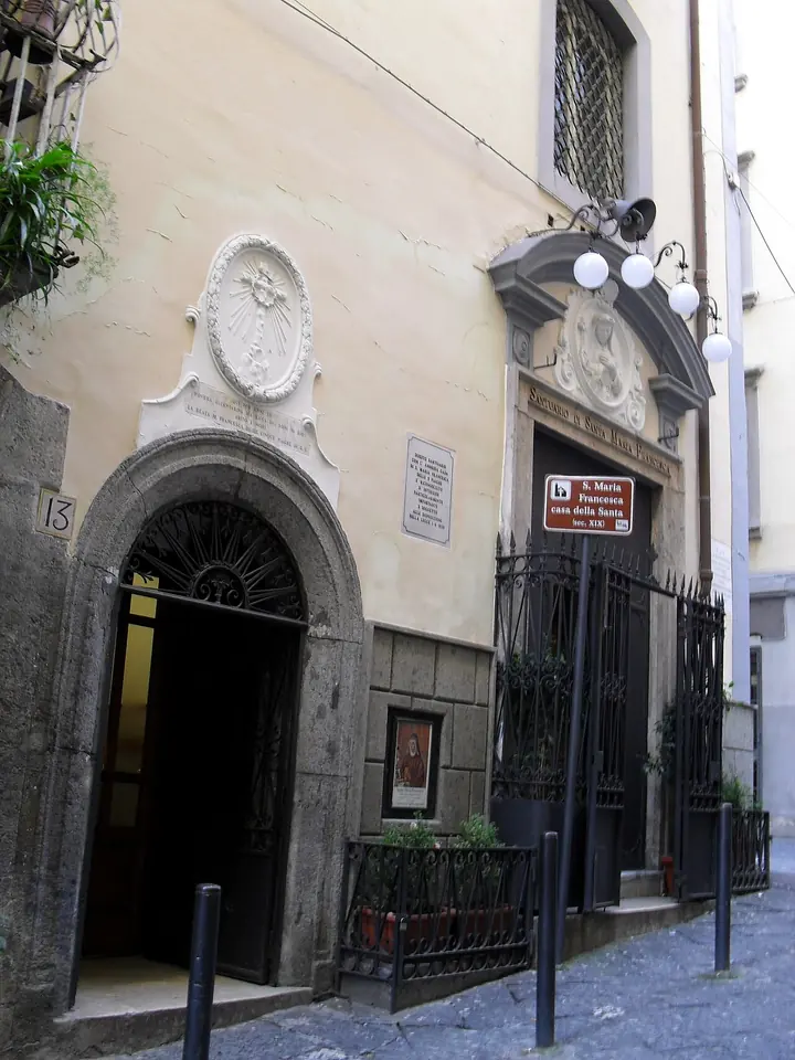 The narrow street entrance of the sanctuary in the house of St. Mary Frances in Naples, with a carved stone doorway and a plaque beside it