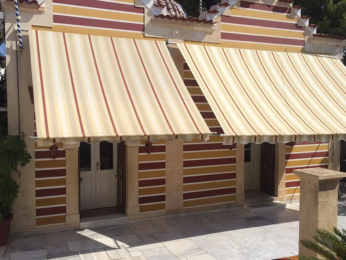 Low monastery church with walls painted in red and cream stripes and two striped awnings over its doors