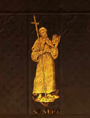 Golden engraved figure of a bearded monk in a long habit holding a tall cross-staff and an open book, with his name below