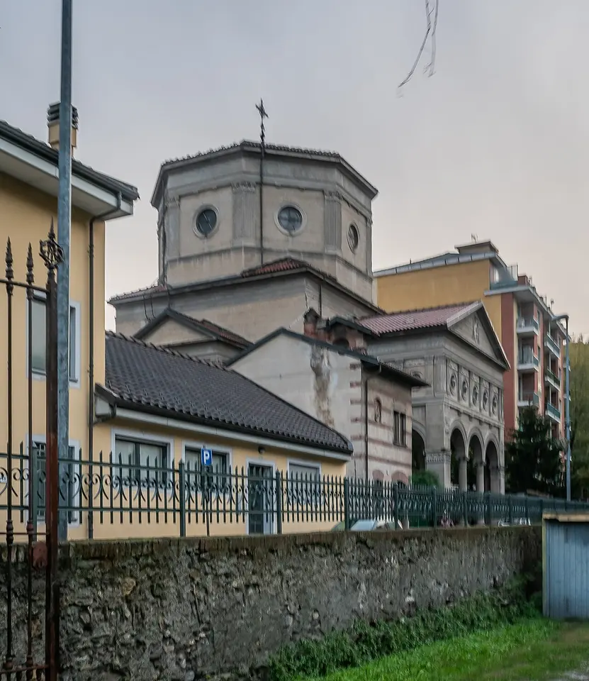 A domed church with an octagonal drum and a classical portico seen beyond a stone wall and iron fence