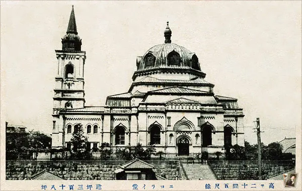 Old picture postcard of a large domed Byzantine-style cathedral with a tall bell tower behind a stone wall, with Japanese writing below