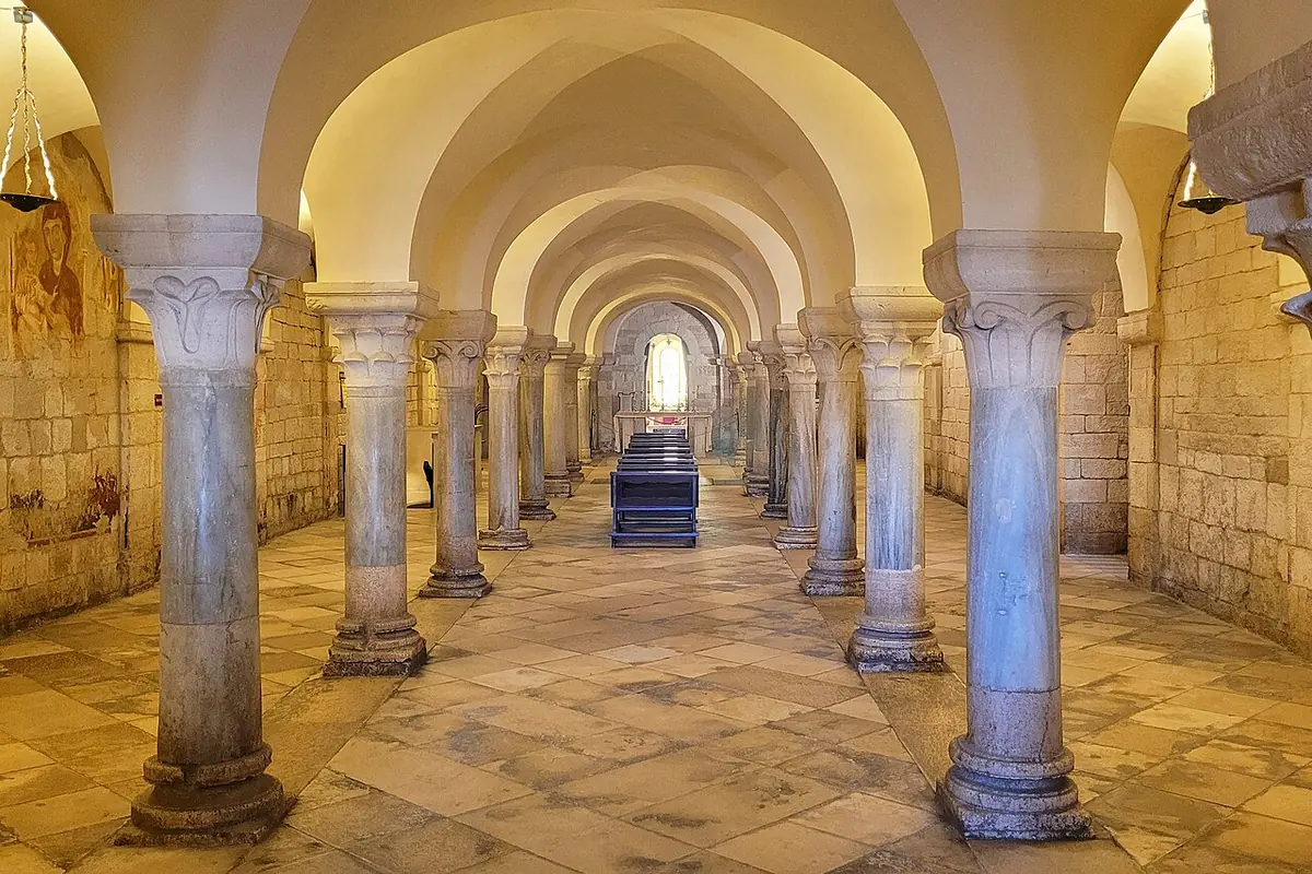 Long vaulted crypt with rows of slender marble columns leading toward an altar
