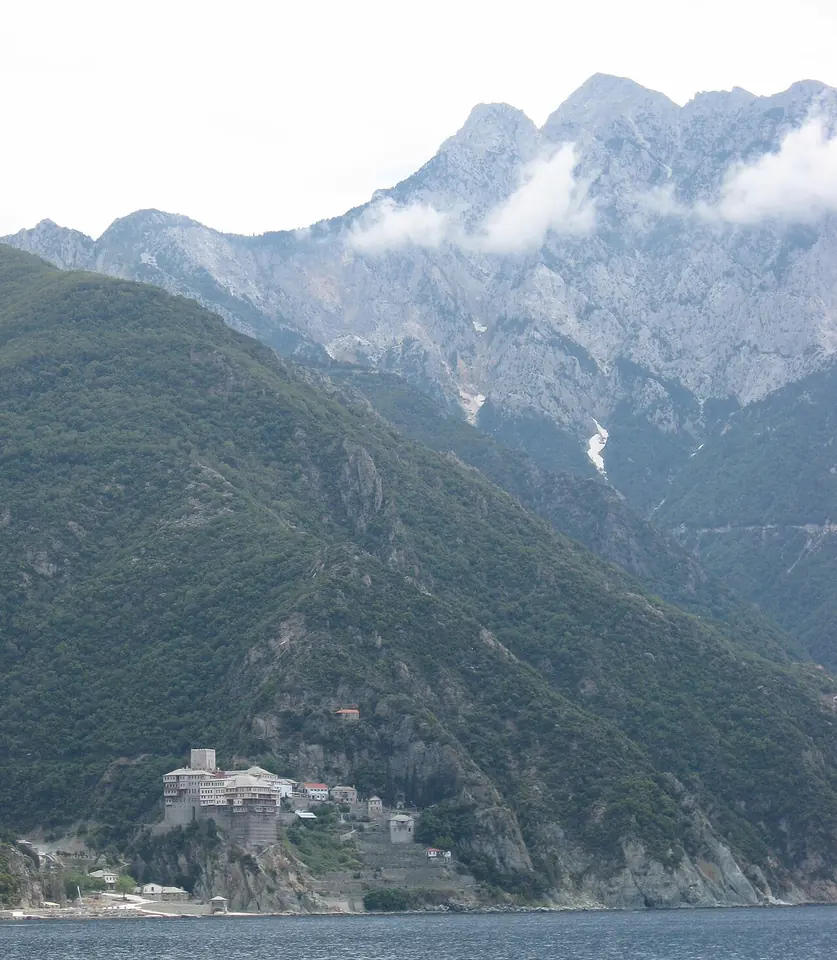 Dionysiou Monastery perched on a cliff above the sea beneath the steep slopes and clouded peak of Mount Athos