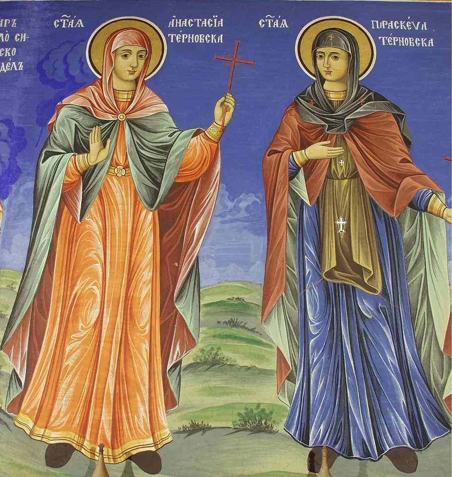 A fresco of two women saints with golden halos standing on green ground, the one on the right in a dark veil, blue robe and red mantle holding a small cross