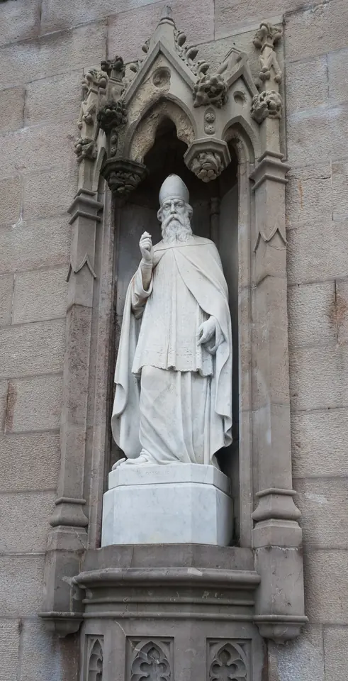 White marble statue of St. Patrick in a bishop's miter and vestments standing in a carved Gothic stone niche