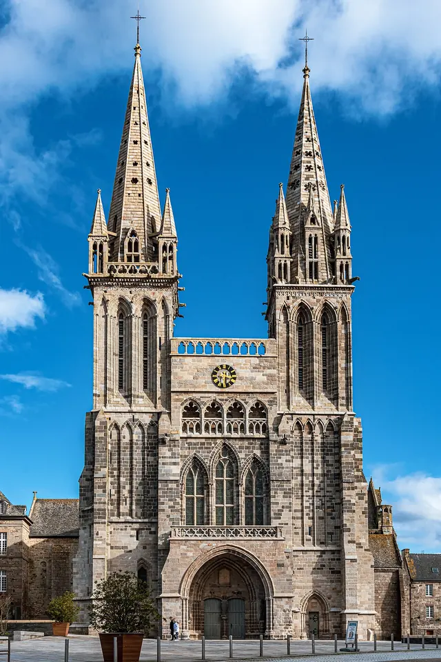 The Gothic west front of the Cathedral of Saint-Paul-Aurélien, with two tall pointed spires against a blue sky