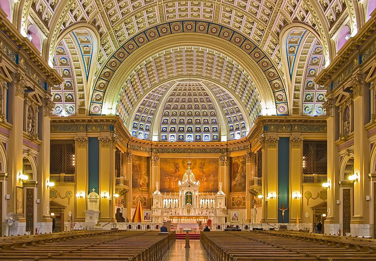 The vast coffered barrel-vaulted nave of Our Lady of Sorrows Basilica in Chicago, lit gold, leading to a high altar