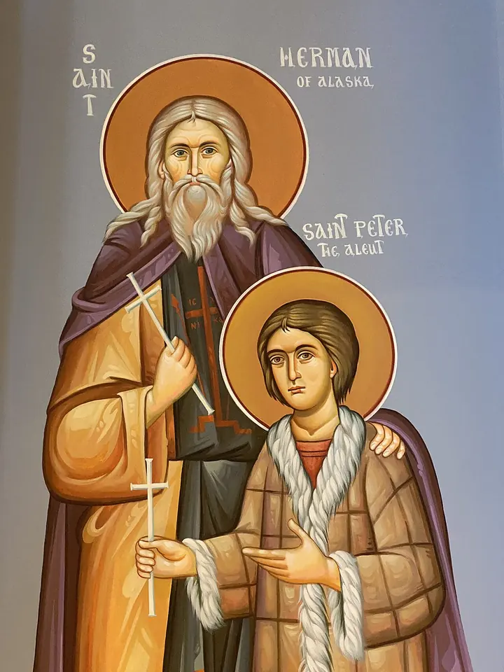 Icon of the white-bearded monk St. Herman of Alaska with his arm around young St. Peter the Aleut, who wears a fur-trimmed parka and holds a cross