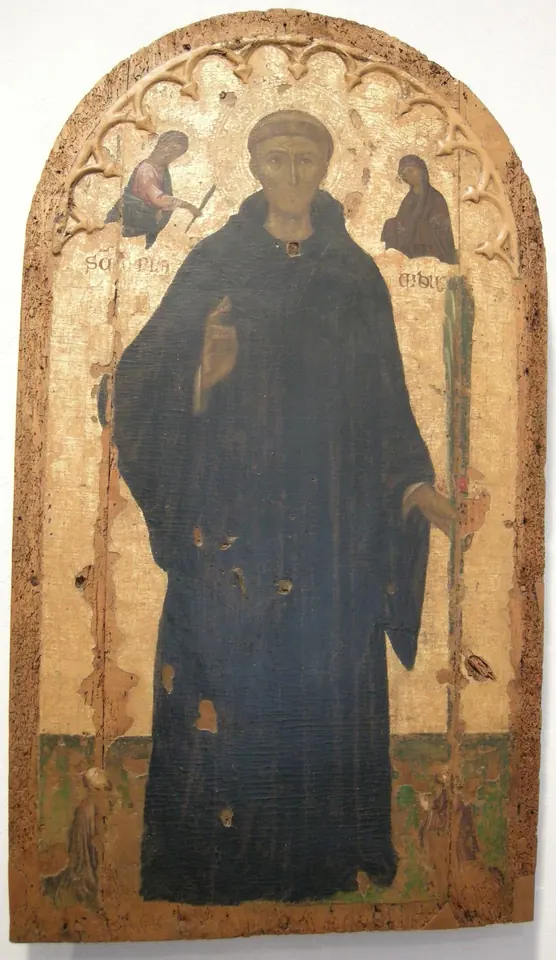 An arched medieval panel painting of a monk in a dark habit standing with his hand raised, with small angels in the upper corners and worn gold background