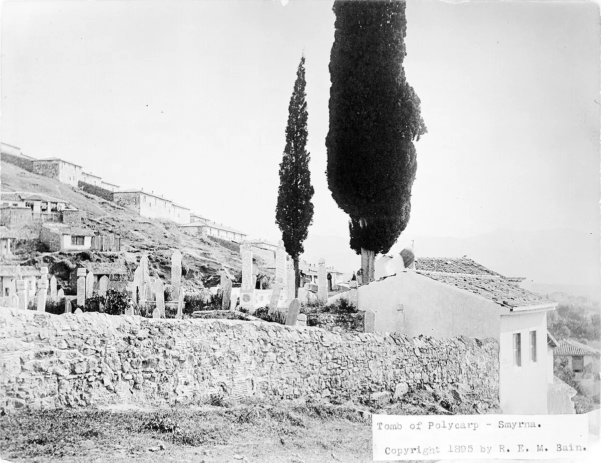 Old black-and-white photograph of a hillside graveyard above Smyrna with two tall cypress trees beside a small white tomb building