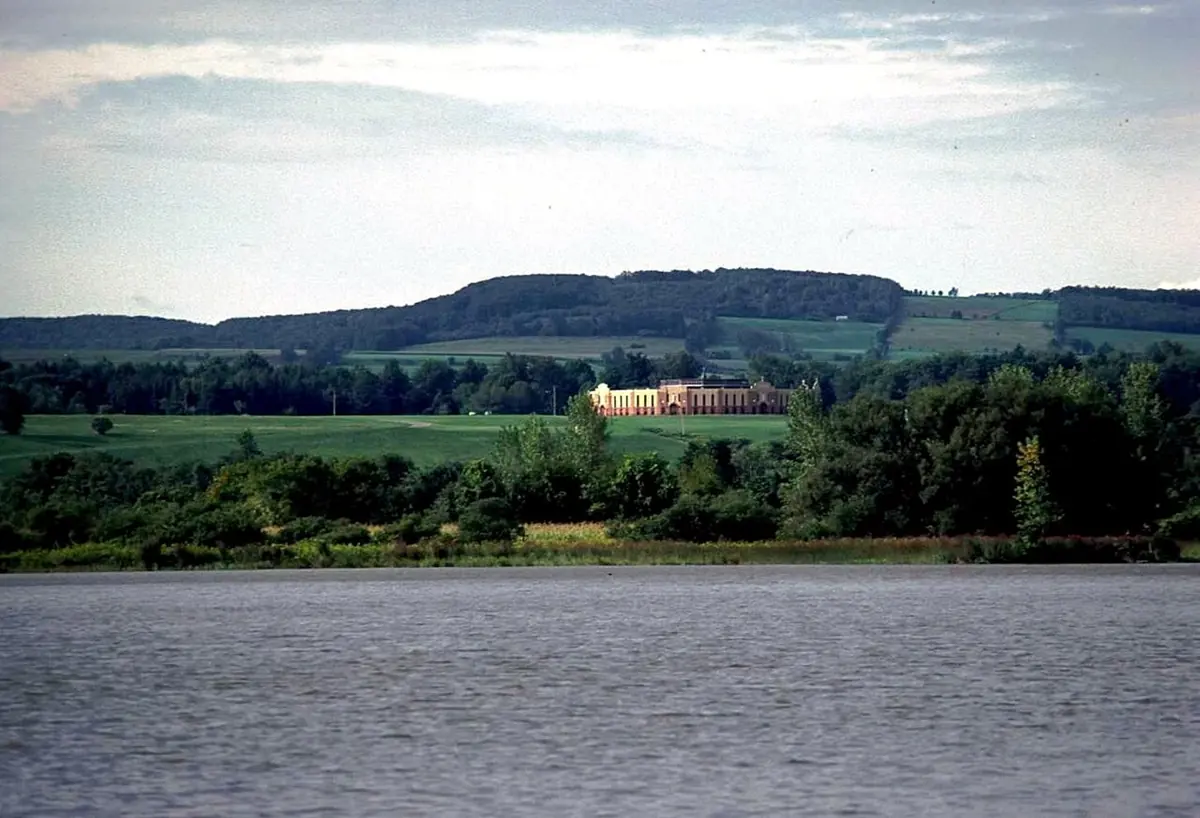 The Mohawk River in the foreground and green hills beyond, with the round white Coliseum church of the Auriesville shrine on the far bank
