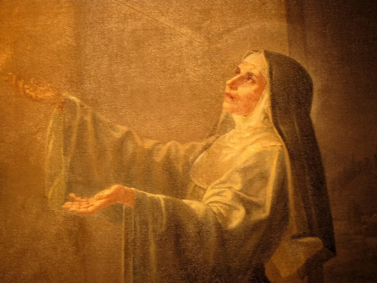 Detail of a painting of St. Rita in a black veil and pale habit, looking up with her hands open in a warm golden light