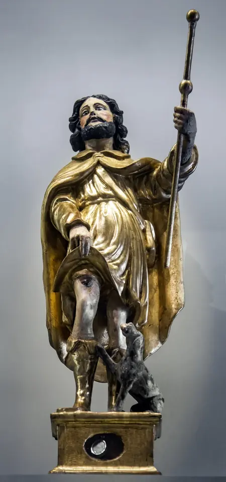A small gilded silver statue of St. Roch with a pilgrim's staff and a dog at his feet, standing on a base with an oval window for a relic
