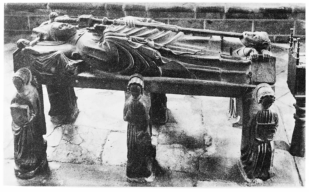 Old black-and-white photograph of a stone tomb with the carved effigy of a bishop lying on top, held up by small carved angel figures