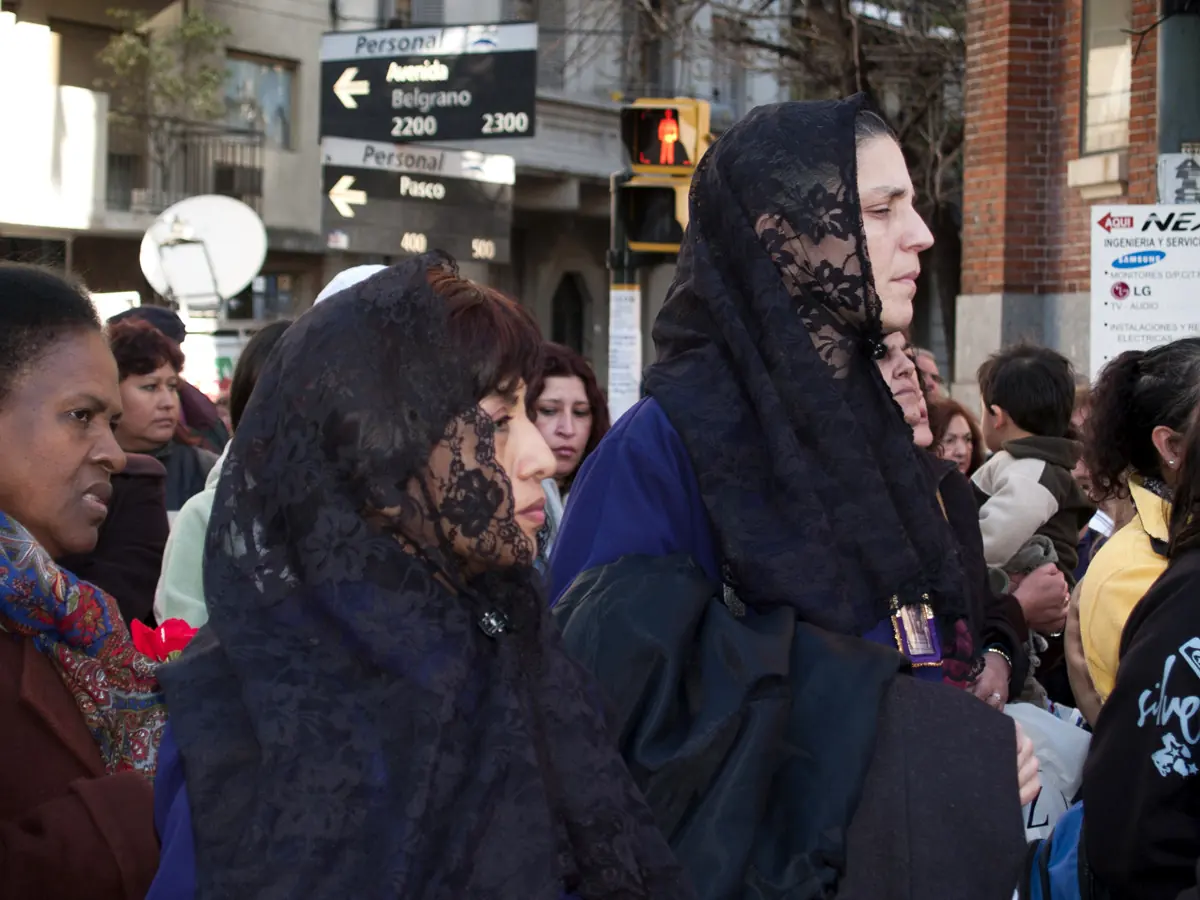 Women in black lace mantillas walking in a crowded street procession in Buenos Aires
