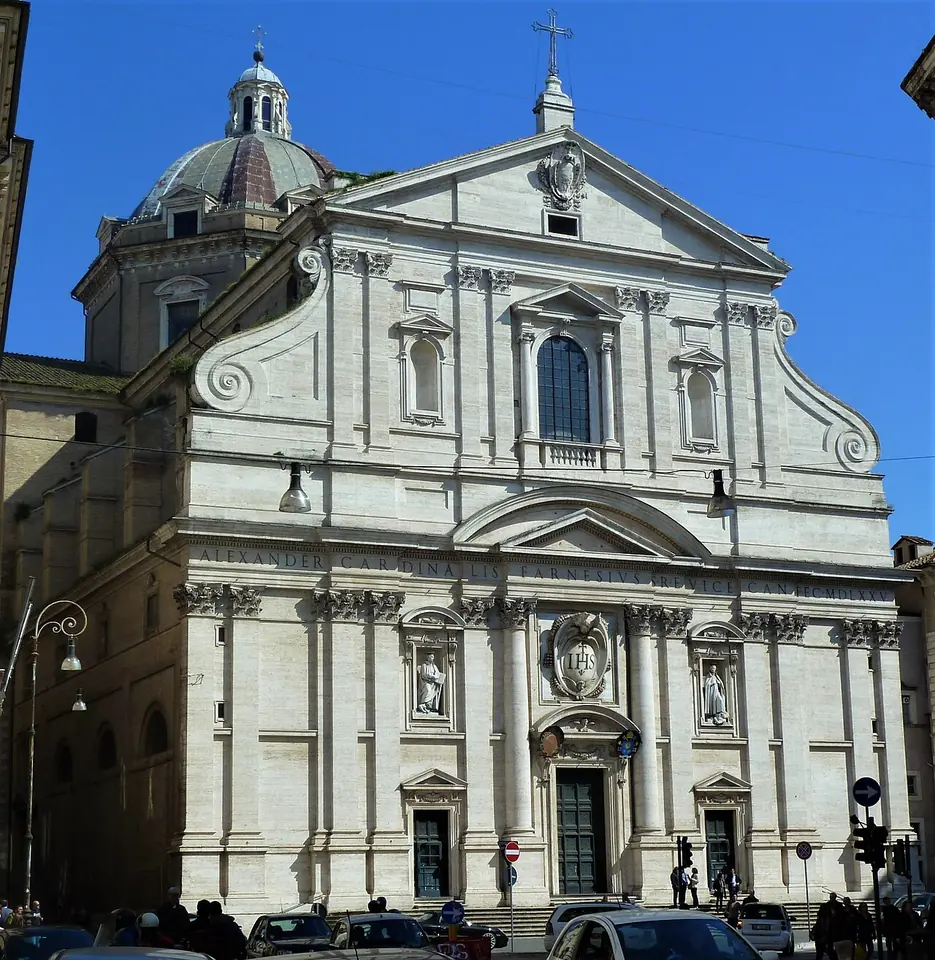 Pale travertine Baroque church facade with paired pilasters, a triangular pediment and large scrolls, seen from the street in Rome