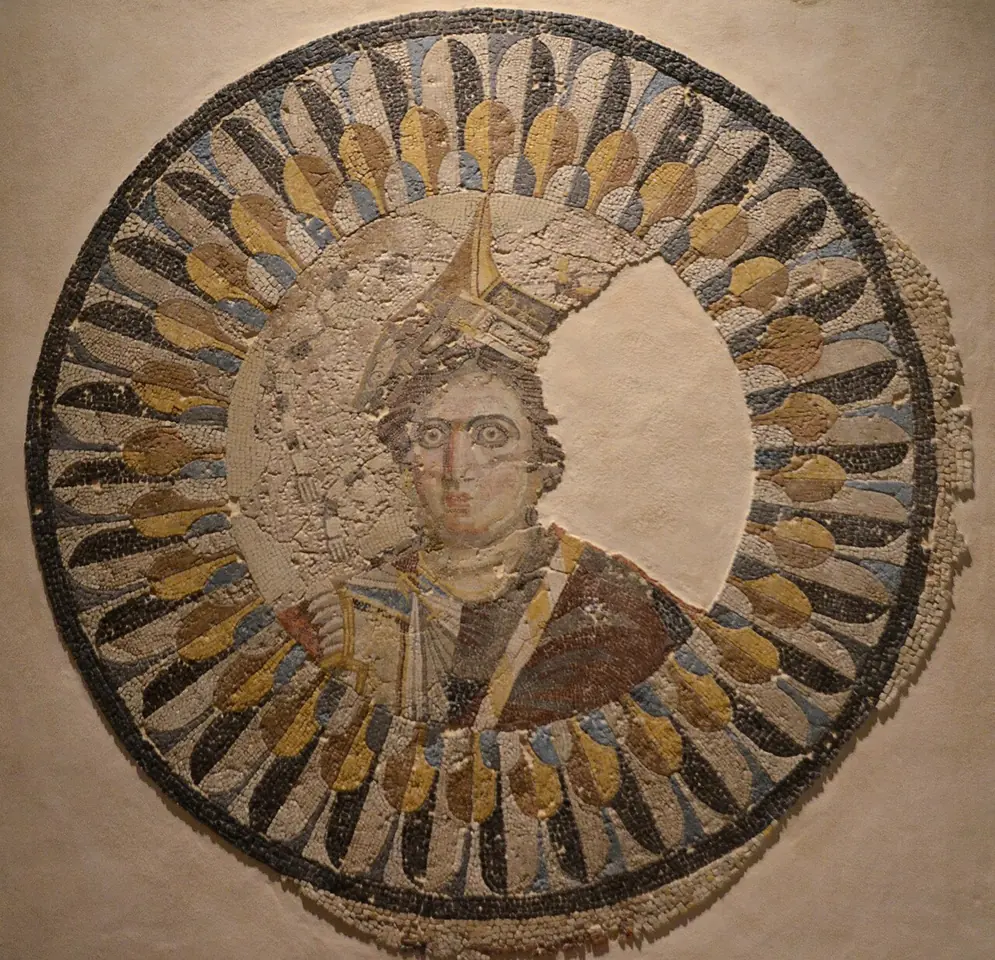 Ancient mosaic portrait of a woman with large dark eyes wearing a headdress shaped like the prow of a warship