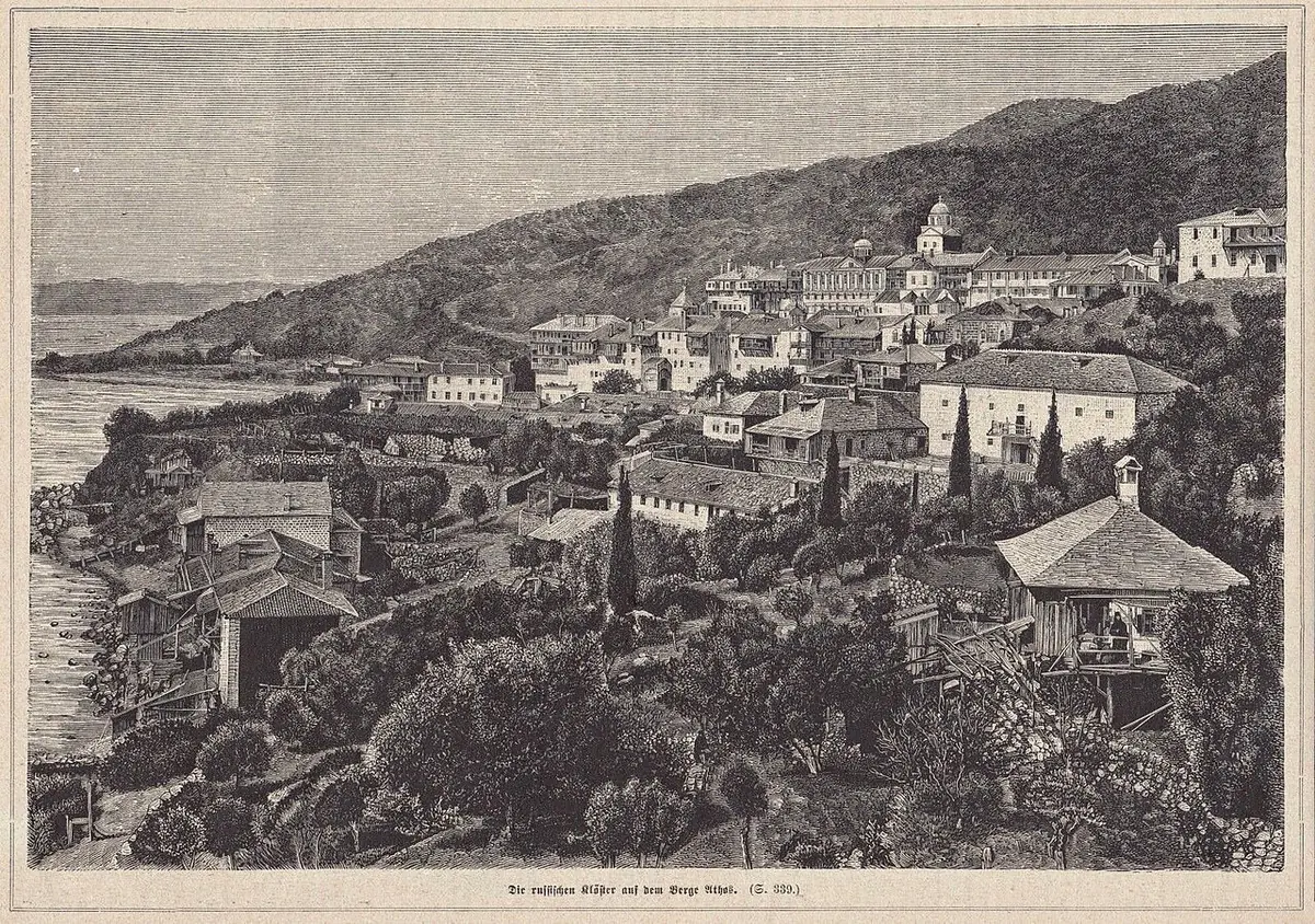 Engraving of a large monastery of many buildings climbing a wooded slope above the sea, seen from a hillside path