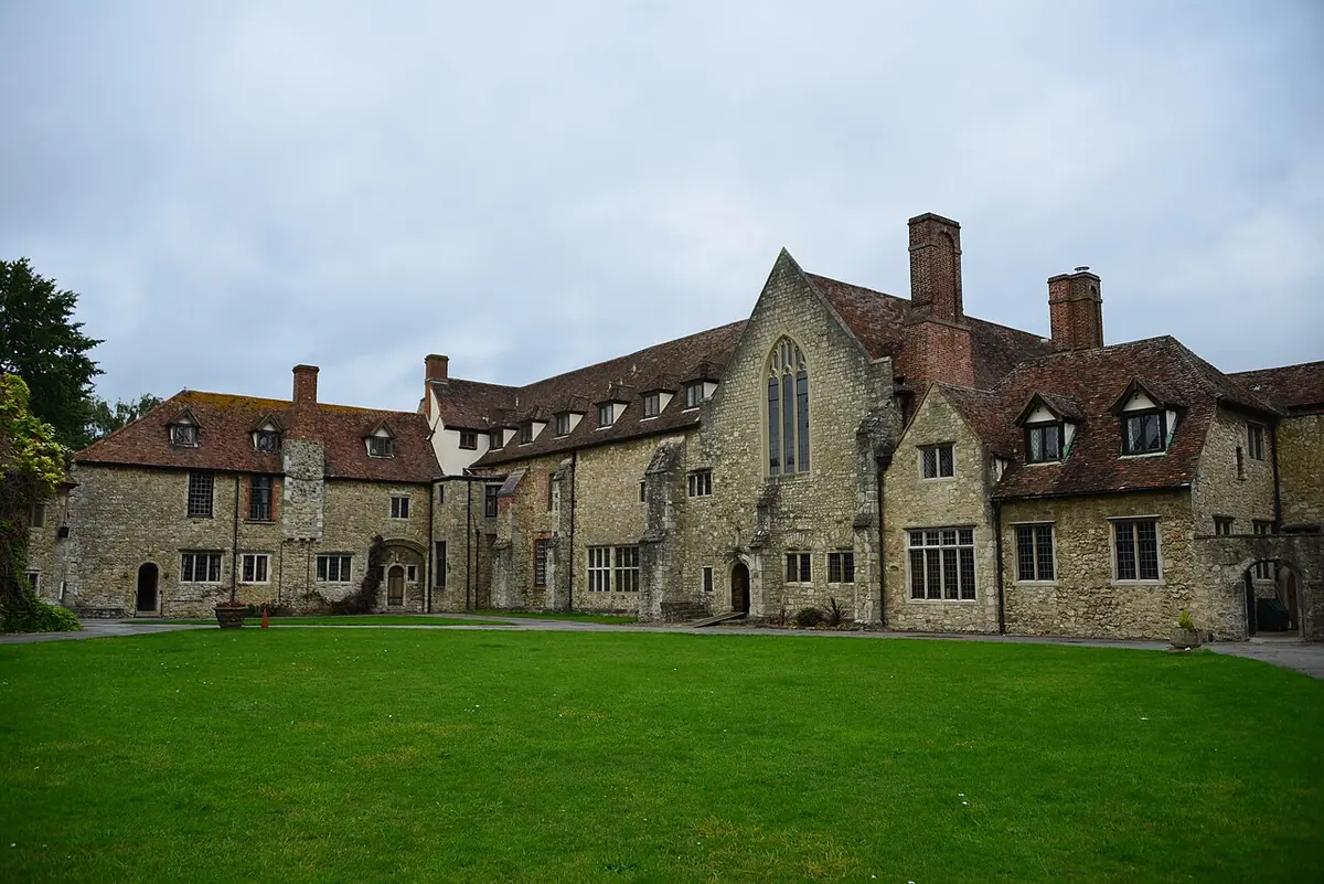 The medieval stone buildings of Aylesford Priory with steep tiled roofs and tall brick chimneys around a green lawn