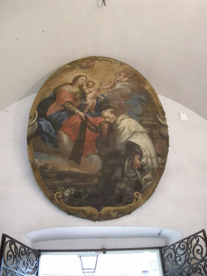 Oval Baroque painting on a convent wall of the Virgin and Child on clouds handing a scapular down to an old white-bearded friar kneeling below