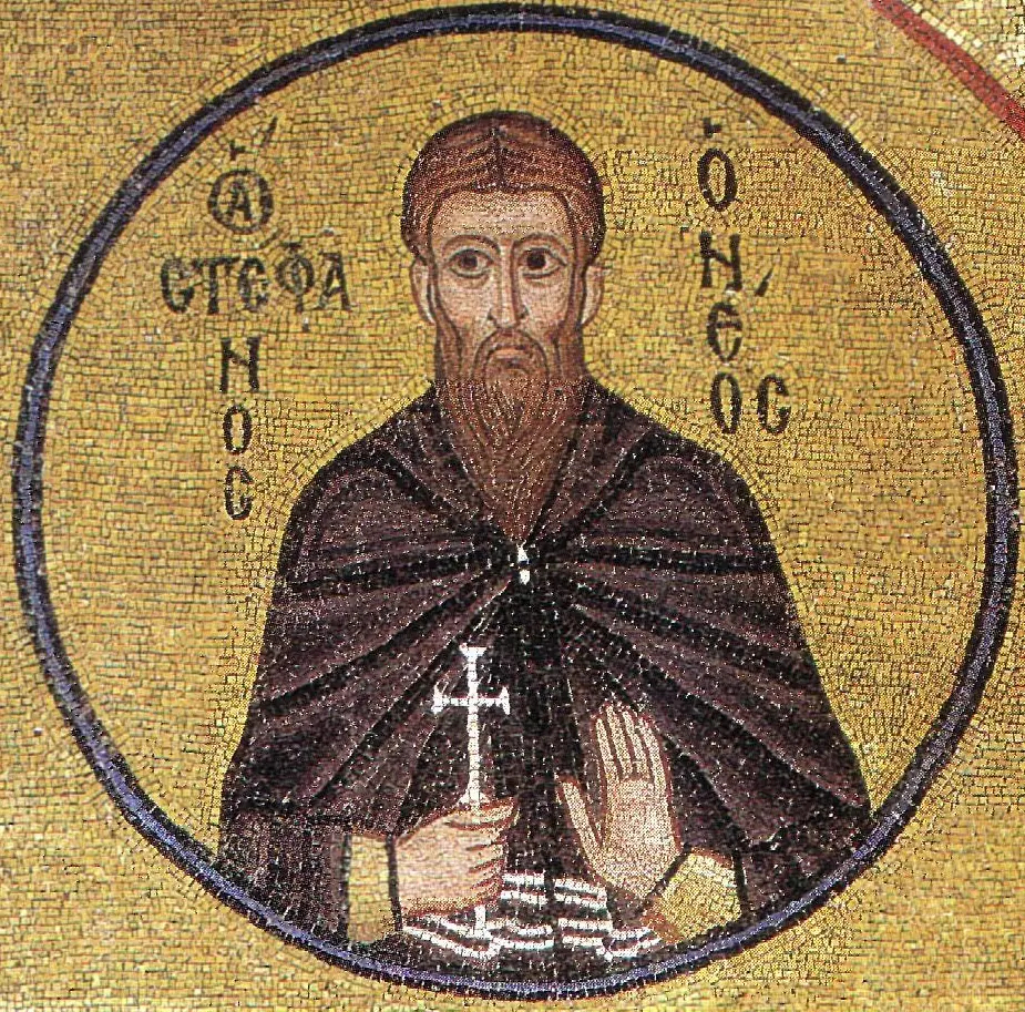 Byzantine gold-ground mosaic medallion of a bearded monk in a dark brown habit holding a small cross, with Greek letters naming him Stephen the New
