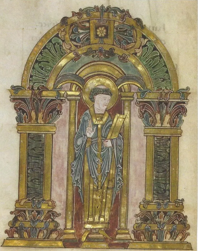 Anglo-Saxon manuscript painting of a tonsured bishop with a halo, in blue and gold vestments, holding a book and raising his hand in blessing, framed by a gold arch with acanthus leaves
