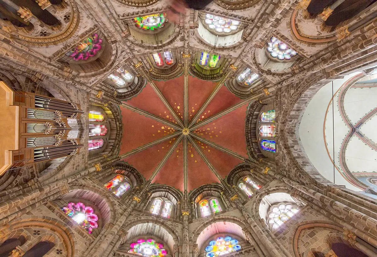Looking up into a ten-sided ribbed dome painted red and gold, ringed with tall stained-glass windows