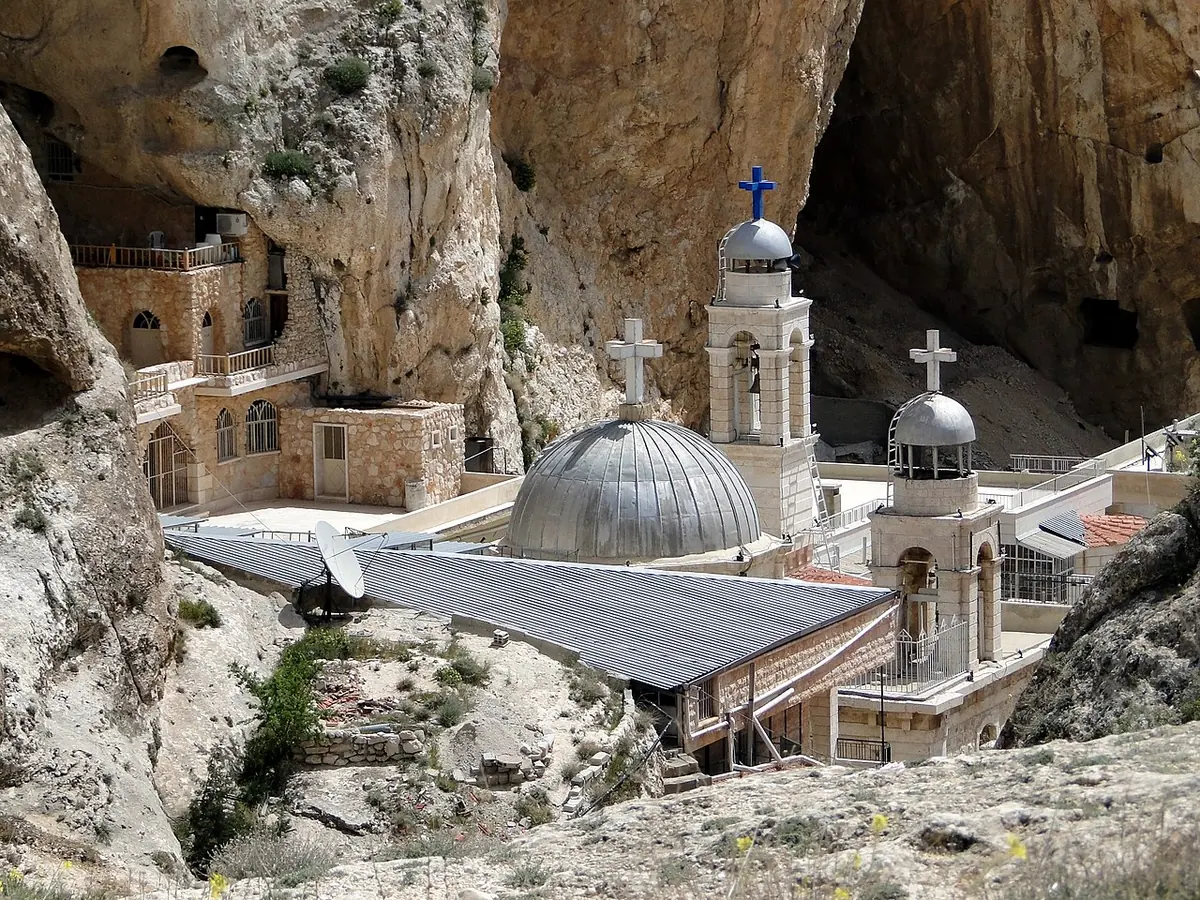 The domed church and buildings of the Convent of St. Thecla tucked under a sheer cliff in the gorge at Maaloula, Syria