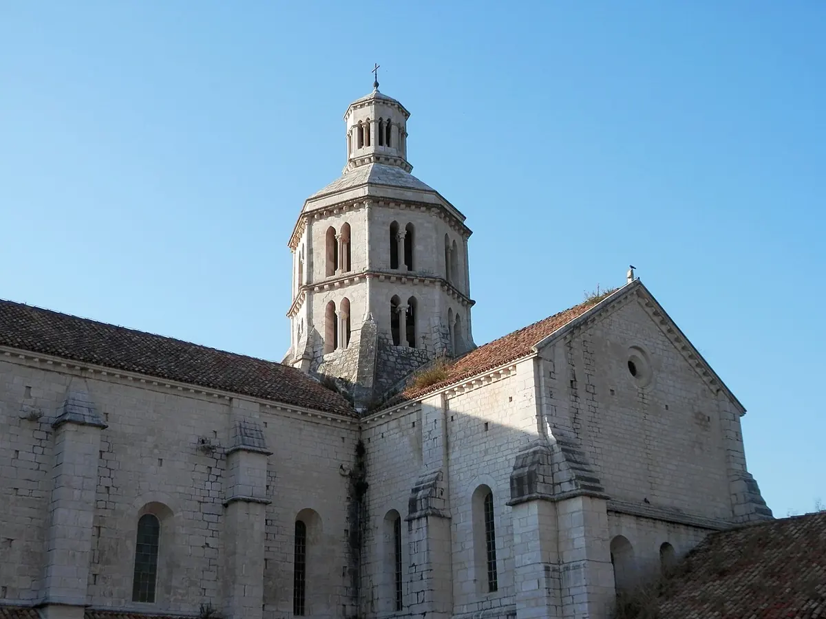 La iglesia de piedra clara de la abadía cisterciense de Fossanova, con su torre octogonal, bajo un cielo azul despejado