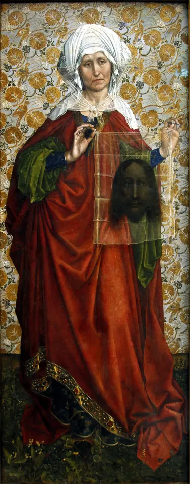 Tall Flemish panel of an older Veronica in a white turban and long red robe, holding a transparent veil with a dark face of Christ before a gold brocade background