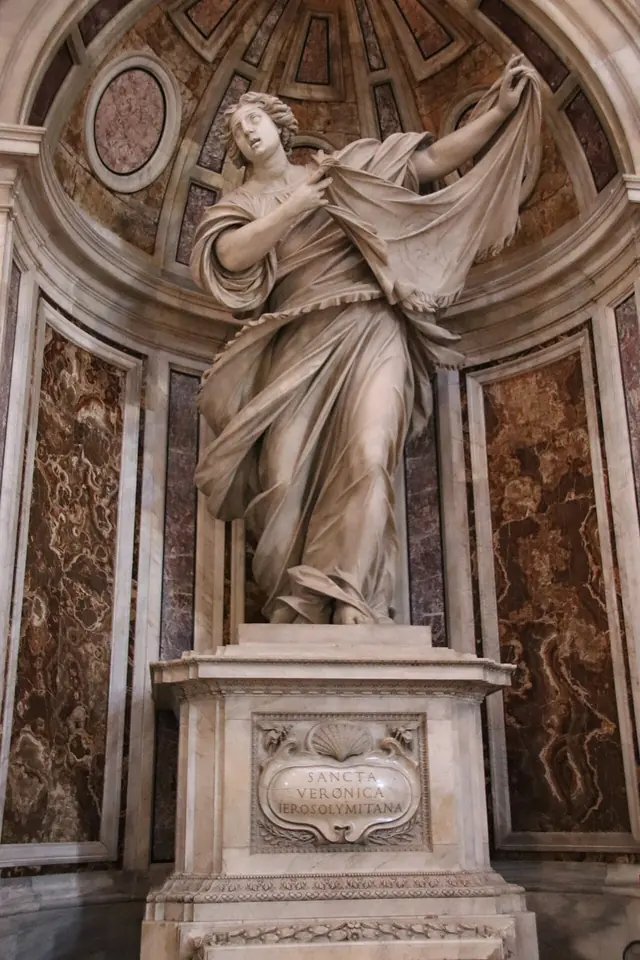 Colossal white marble statue of Veronica striding forward with her veil flying out in both hands, set in a niche of colored marble