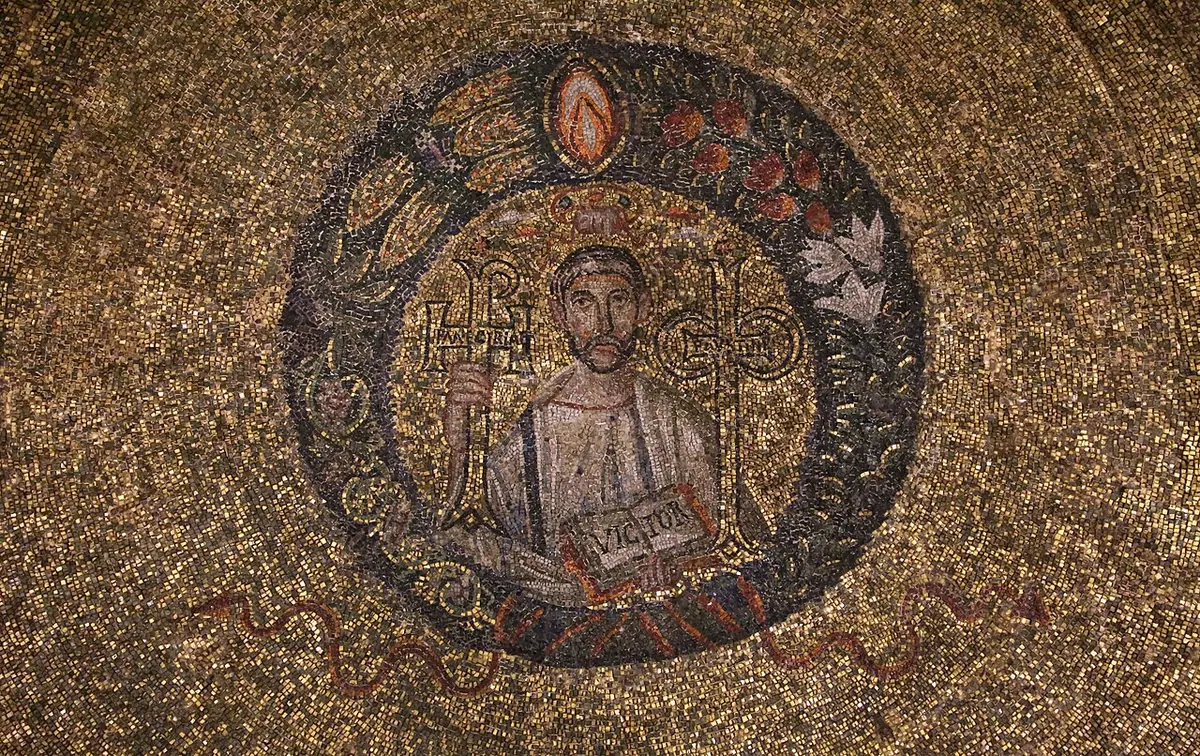 A fifth-century mosaic medallion of St. Victor, a young bearded man between two jeweled crosses holding an open book, set in a golden dome