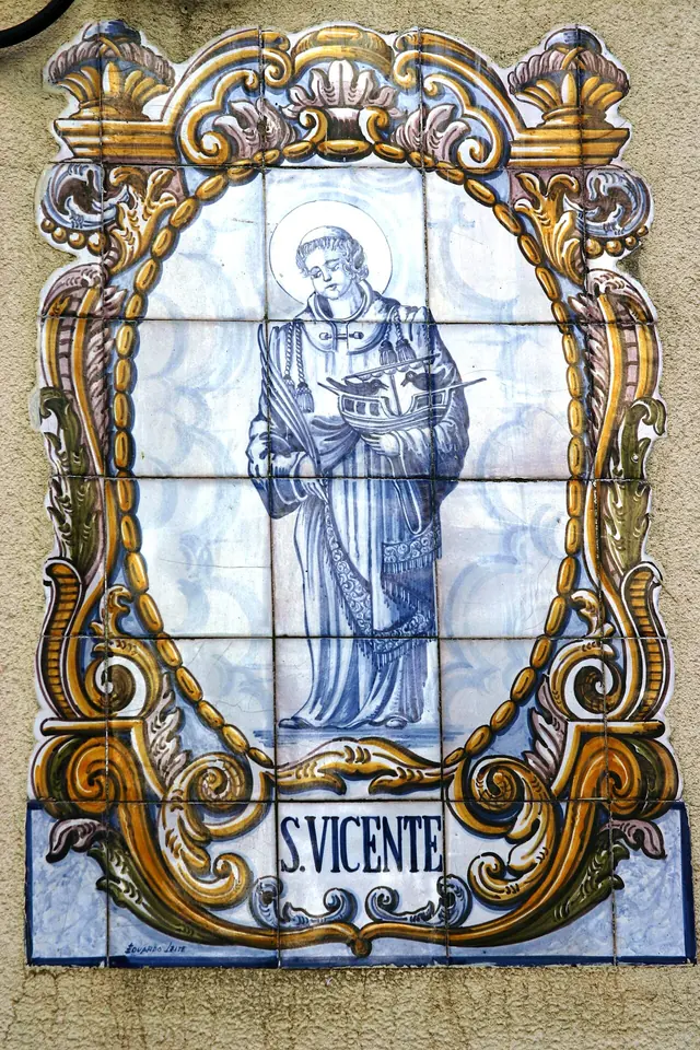 Blue-and-white Portuguese tile panel in a yellow Baroque frame showing St. Vincent holding a palm and a small ship with ravens, labeled S. Vicente