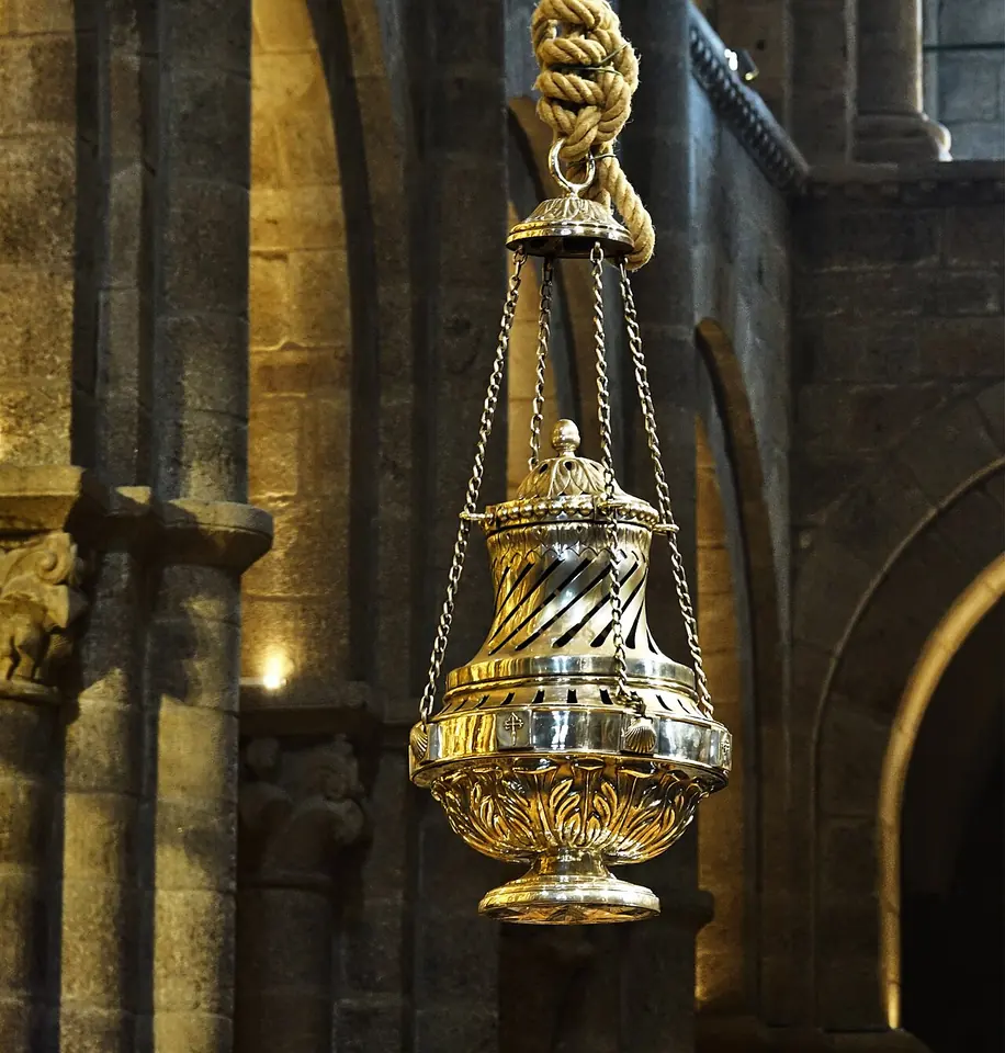 The huge silver-plated Botafumeiro censer hanging from a thick rope among the stone arches of the cathedral, its body covered in swirling ribs and leaves