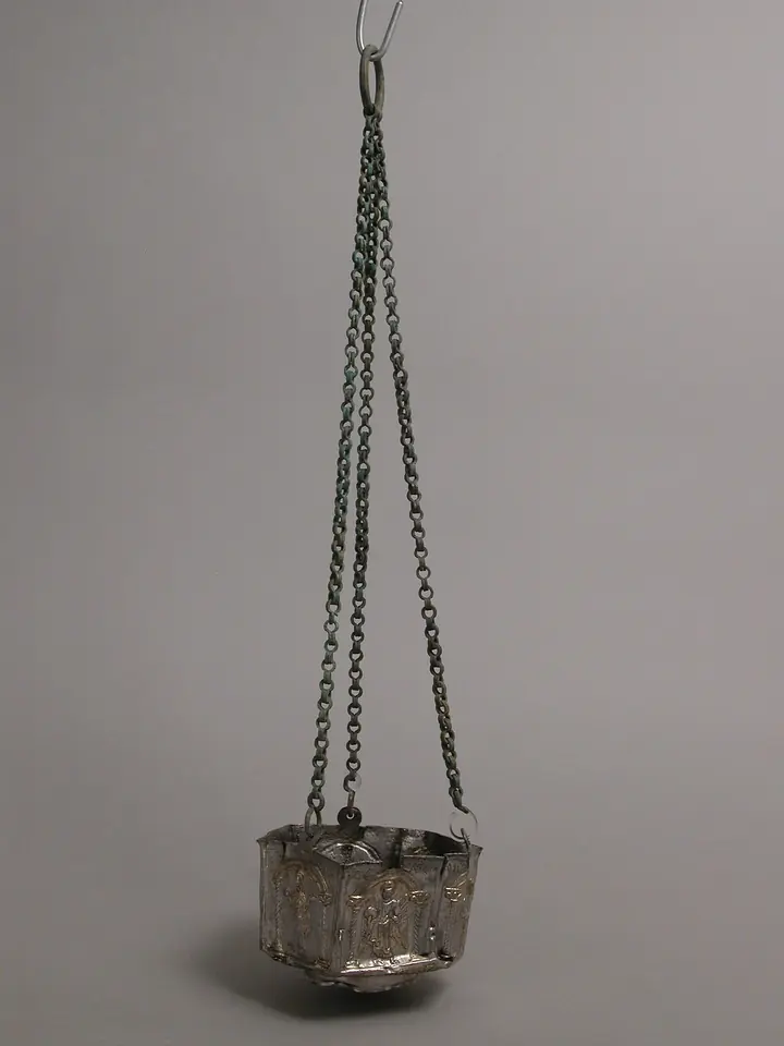A small silver censer from the Byzantine Empire hanging from three long chains, its sides decorated with standing holy figures