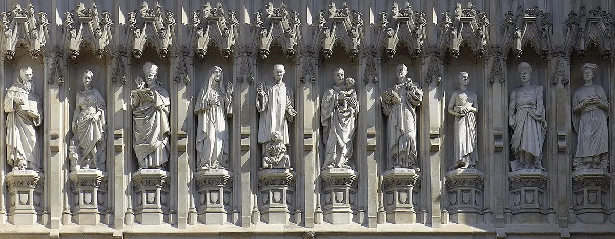 Row of ten white stone statues in Gothic niches on the front of a church, each a different man or woman of the 20th century