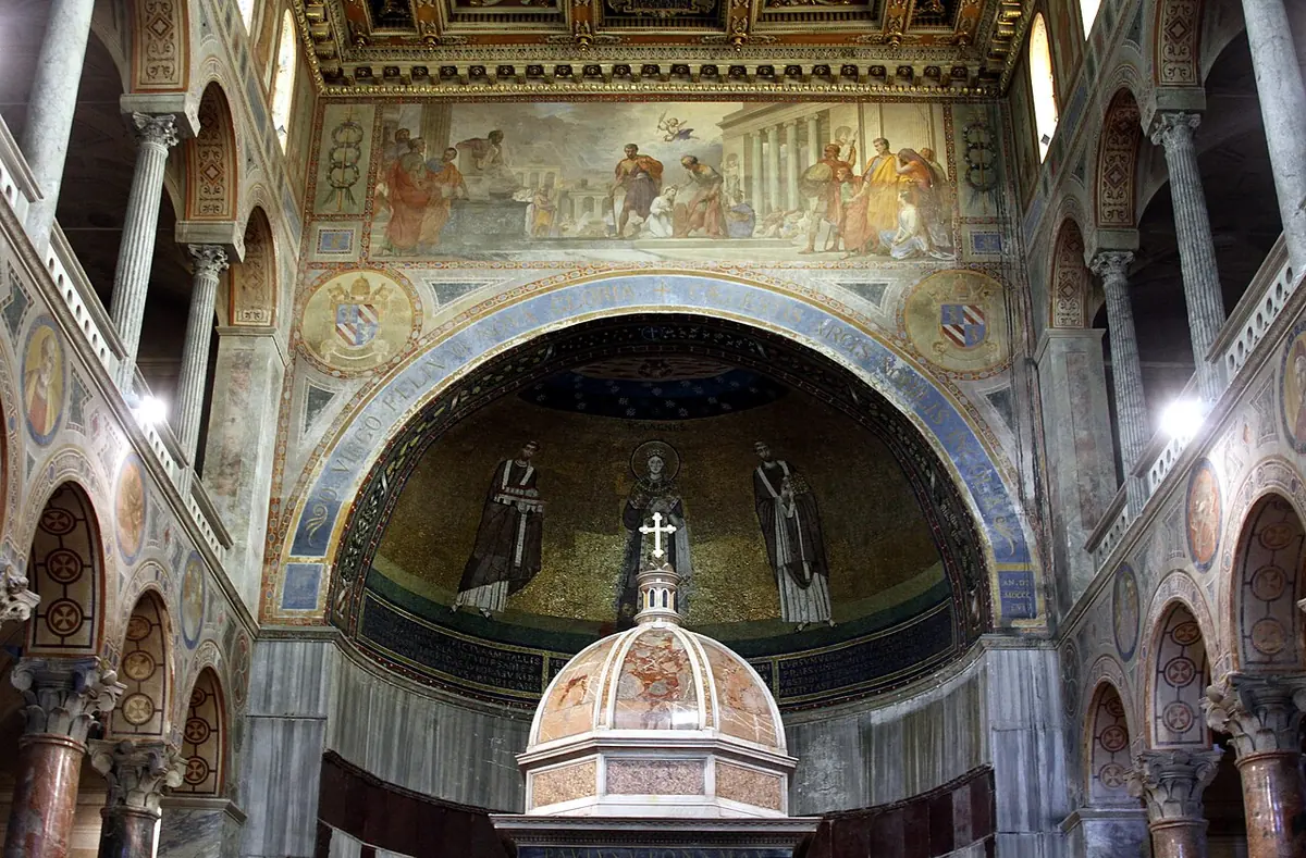 Church apse with a gold mosaic of St. Agnes standing between two popes, above a canopied altar under a carved arch